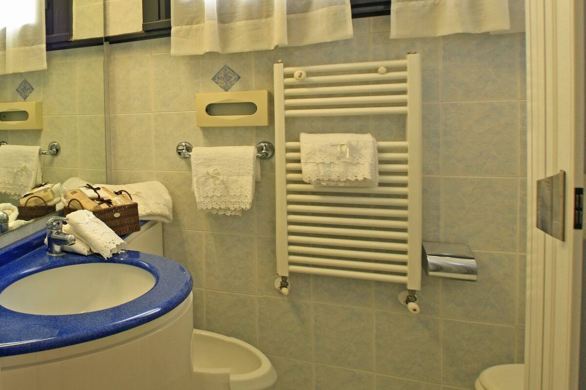 A bathroom with a sink, mirror, towel rack, and a toilet.