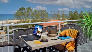 Un balcon, un ordinateur portable, un verre de lait, un carnet et un chapeau.