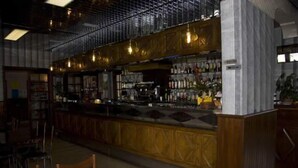 A bar area with wooden cabinets, a counter, and hanging lights. - Hôtel des Rochers (Marvejols)