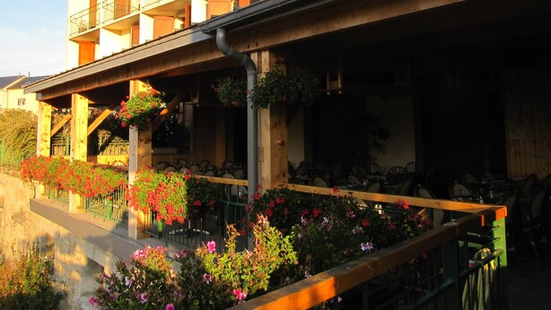 A multi-story hotel with balconies, outdoor seating, and flower arrangements. - Hôtel des Rochers (Marvejols)