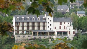 A multi-story hotel with balconies and a flat roof, surrounded by greenery. - Hôtel des Rochers (Marvejols)