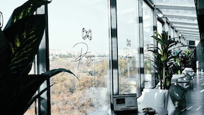 Un interior moderno con amplias ventanas, zonas de estar y plantas en macetas.