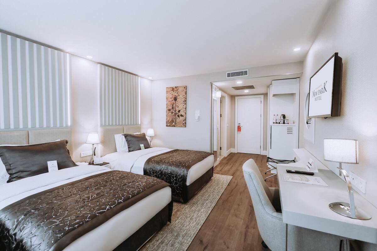 Ein Hotelzimmer mit zwei Betten, einem Schreibtisch und einem Spiegel.