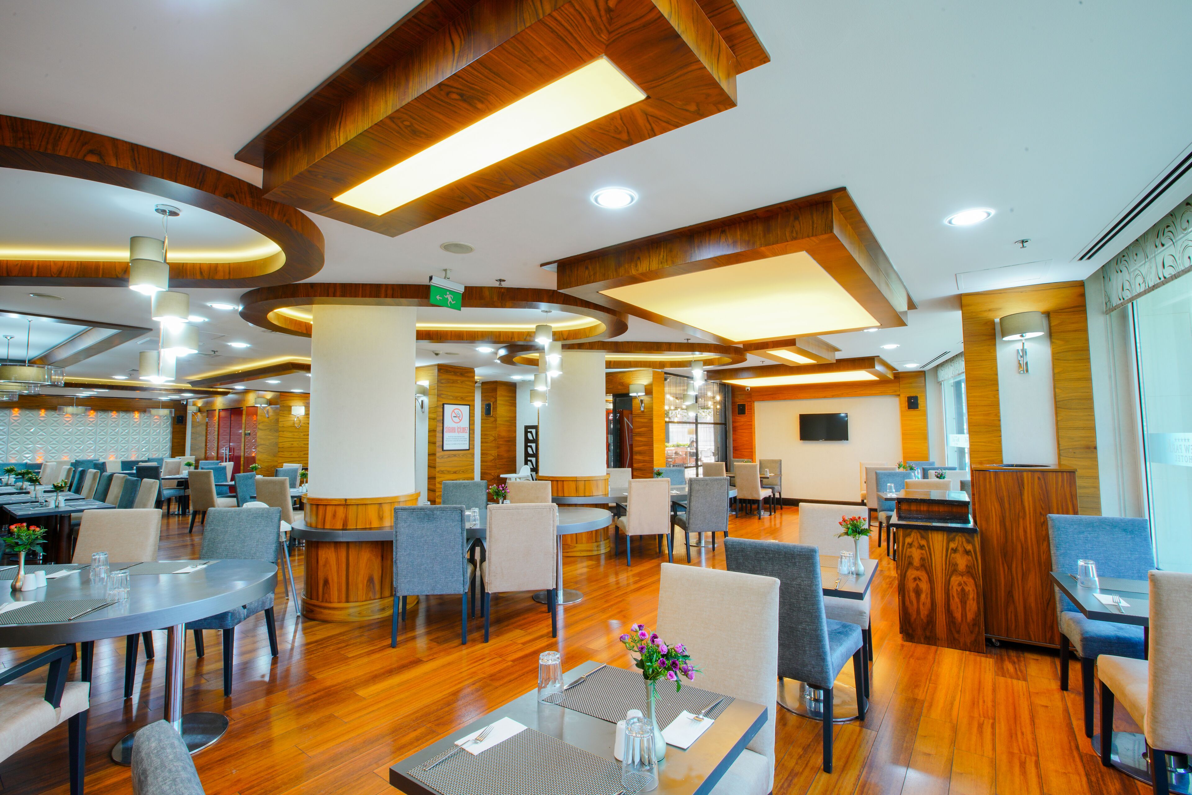 Un hall d’hôtel spacieux, doté de plusieurs espaces salon, d’éléments décoratifs en bois et d’un bar central.