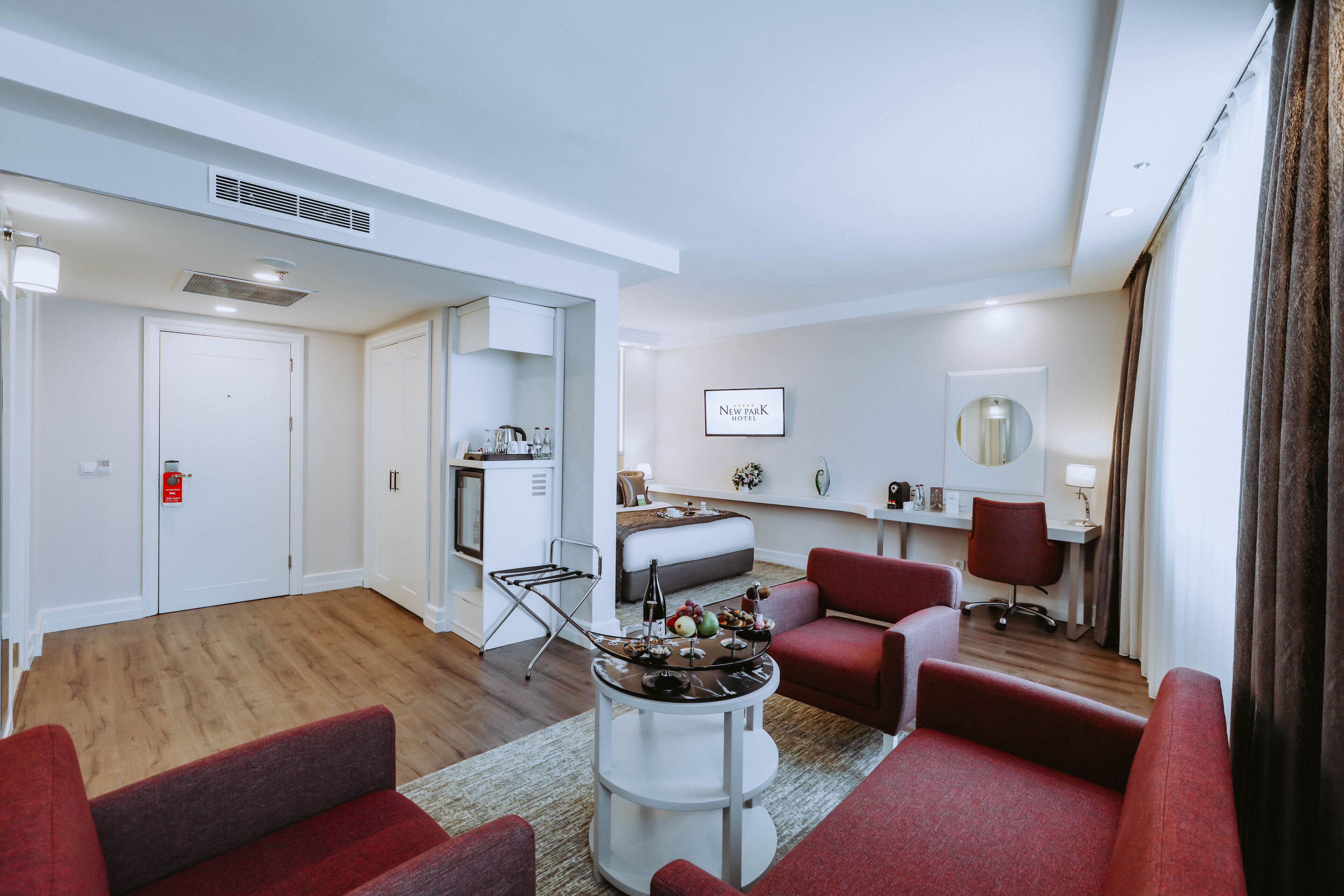 A modern hotel room with a living area, a dining table, and a separate bedroom.