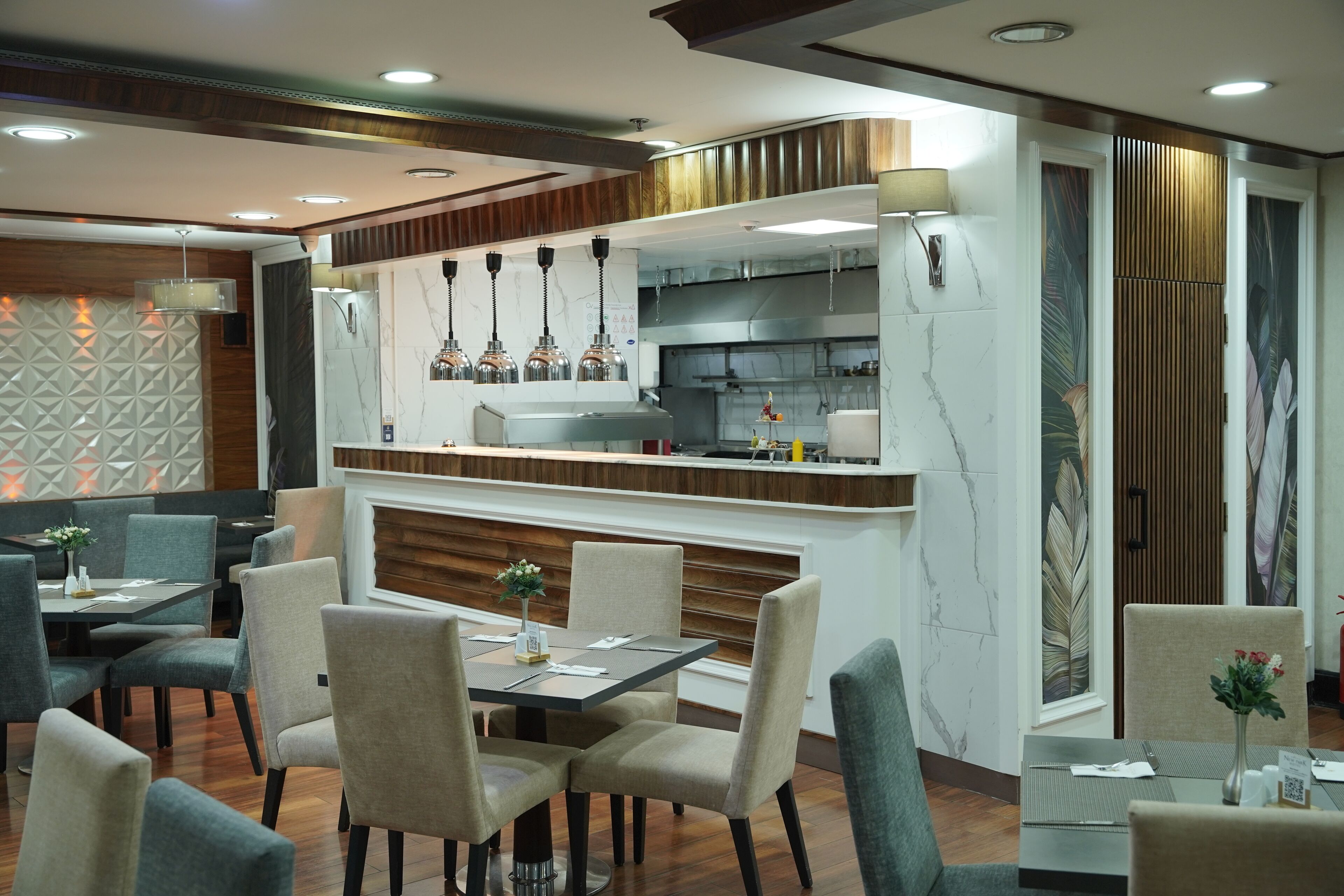 A modern restaurant with a central bar, seating arrangements, and a decorative wall.