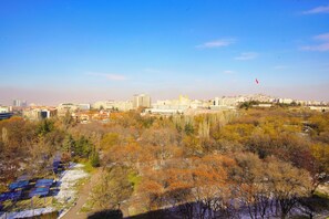 Un paisaje urbano con una mezcla de edificios modernos y antiguos, cielo despejado y un parque con árboles y paneles solares.