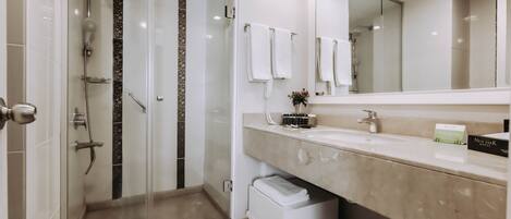 A modern bathroom with a glass-enclosed shower, a vanity with a mirror, and a toilet.