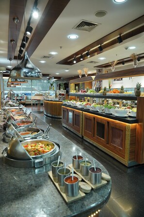 Zona de bufé con varias estaciones de comida, incluyendo una olla caliente y una variedad de platos.