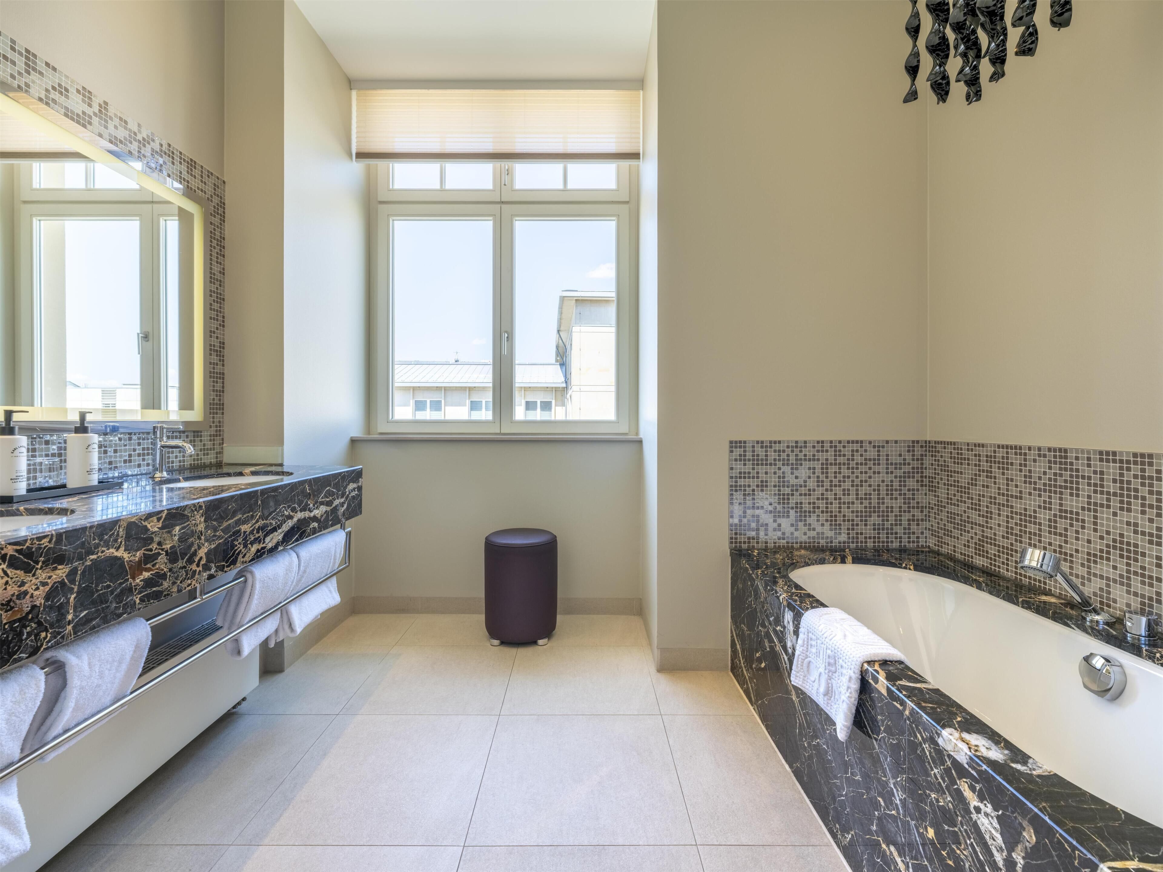 Ein modernes Badezimmer mit einem großen Spiegel, einer Badewanne und einem Waschtisch mit Marmorplatte.