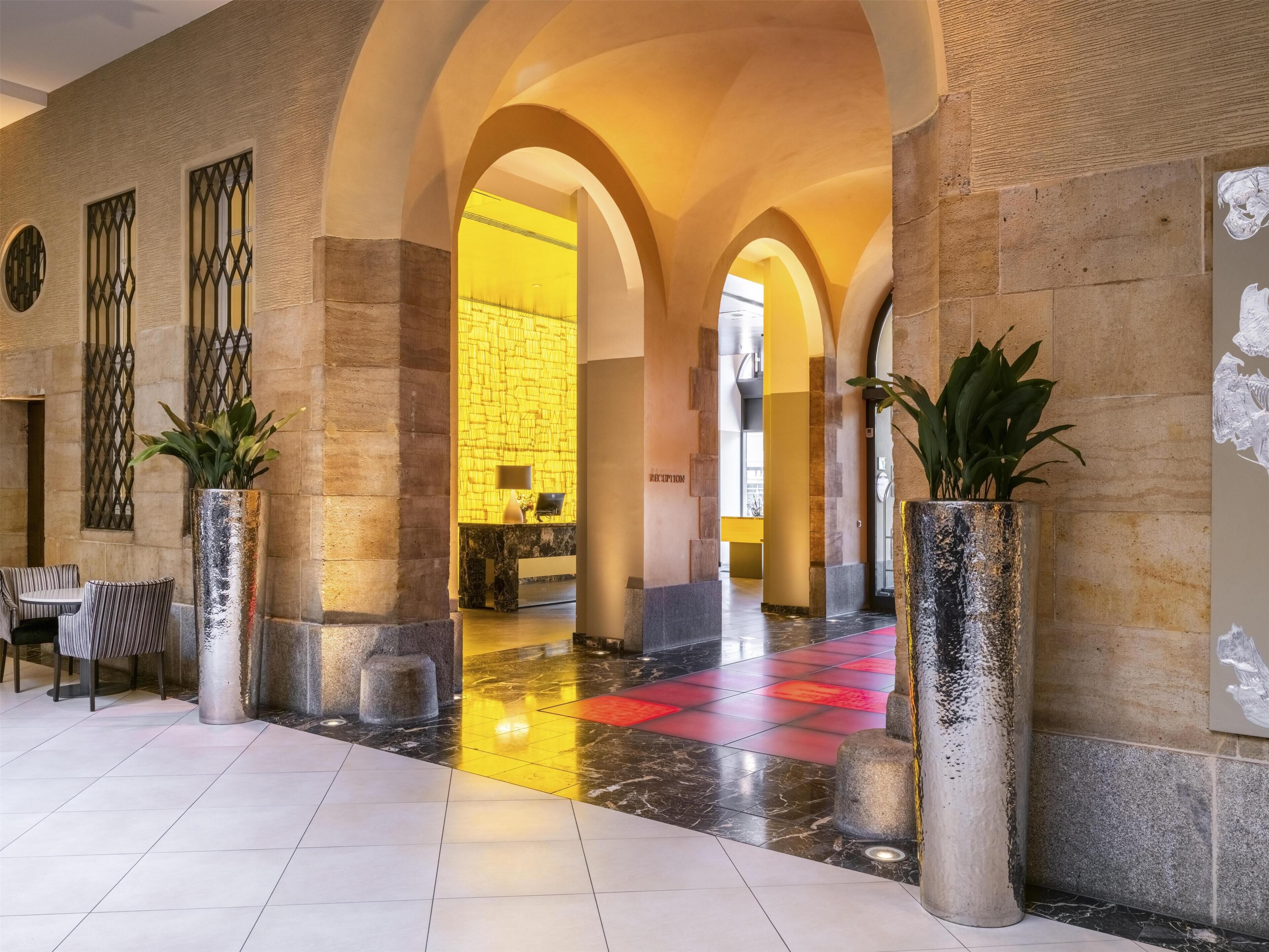 Een hotel lobby met een receptiebalie, een zithoek en een incheckbalie.
