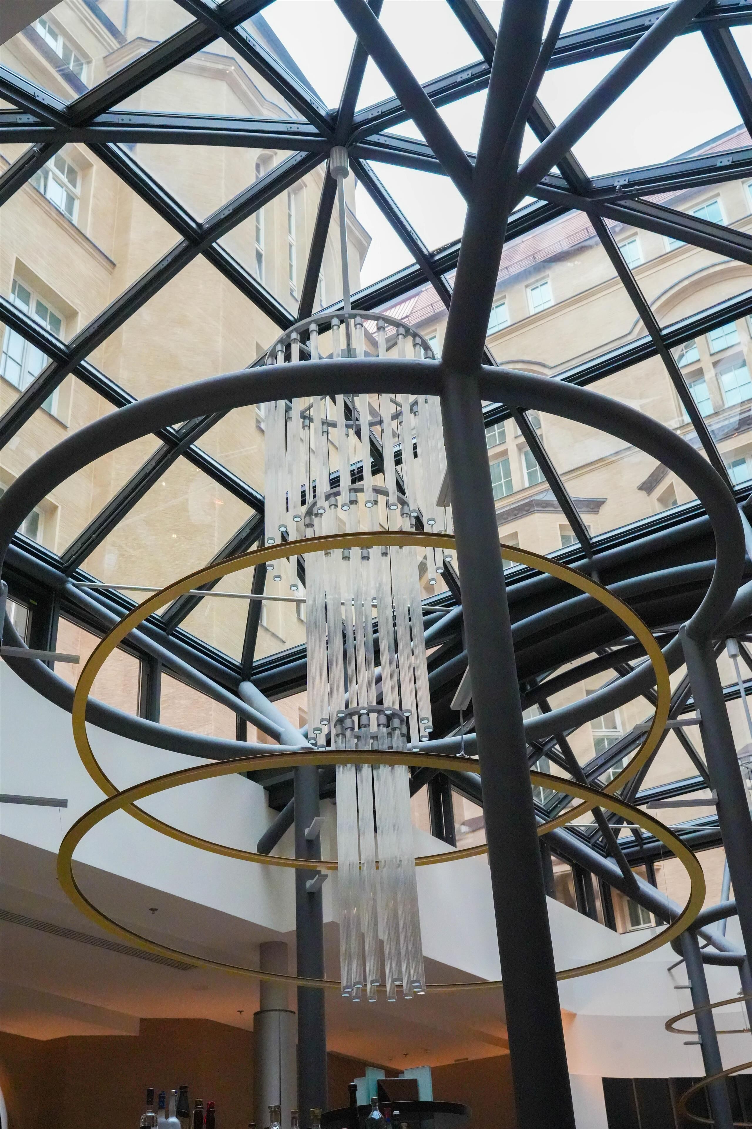Un interior moderno con una estructura metálica geométrica y una lámpara colgante central.