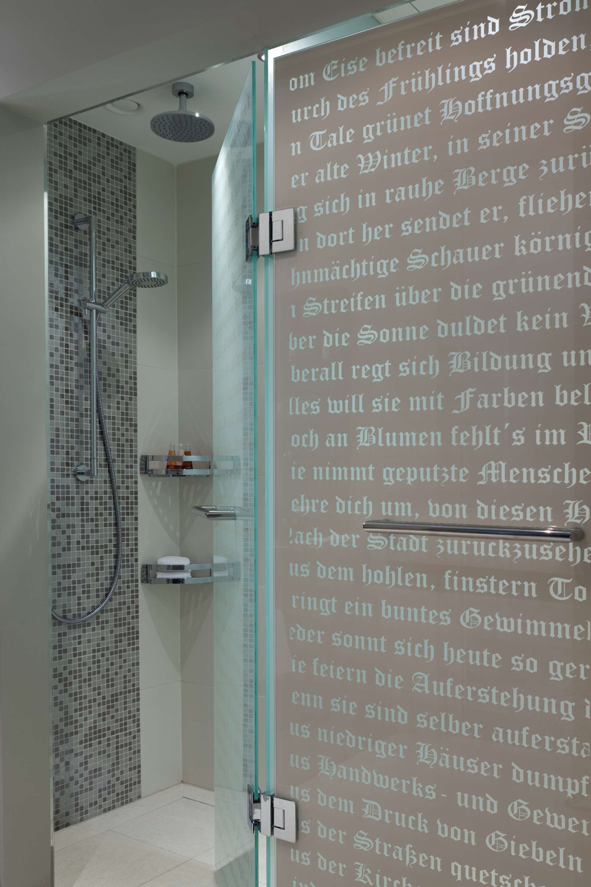 A modern bathroom with a glass shower enclosure, a tiled floor, and a glass door.