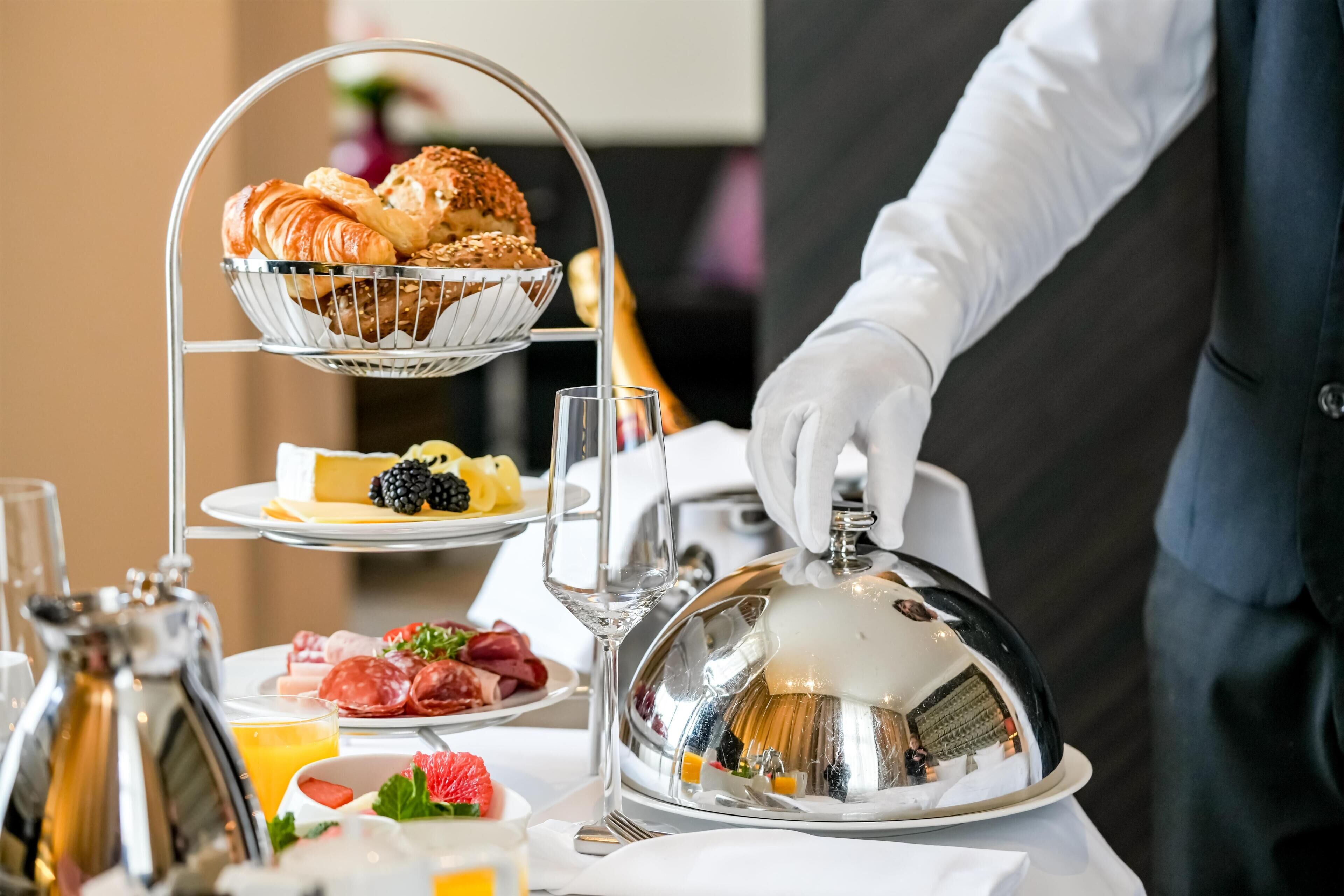 Un bufé de desayuno con croissants, queso, frambuesas y carnes.