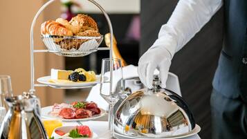 Un bufé de desayuno con croissants, queso, frambuesas y carnes.