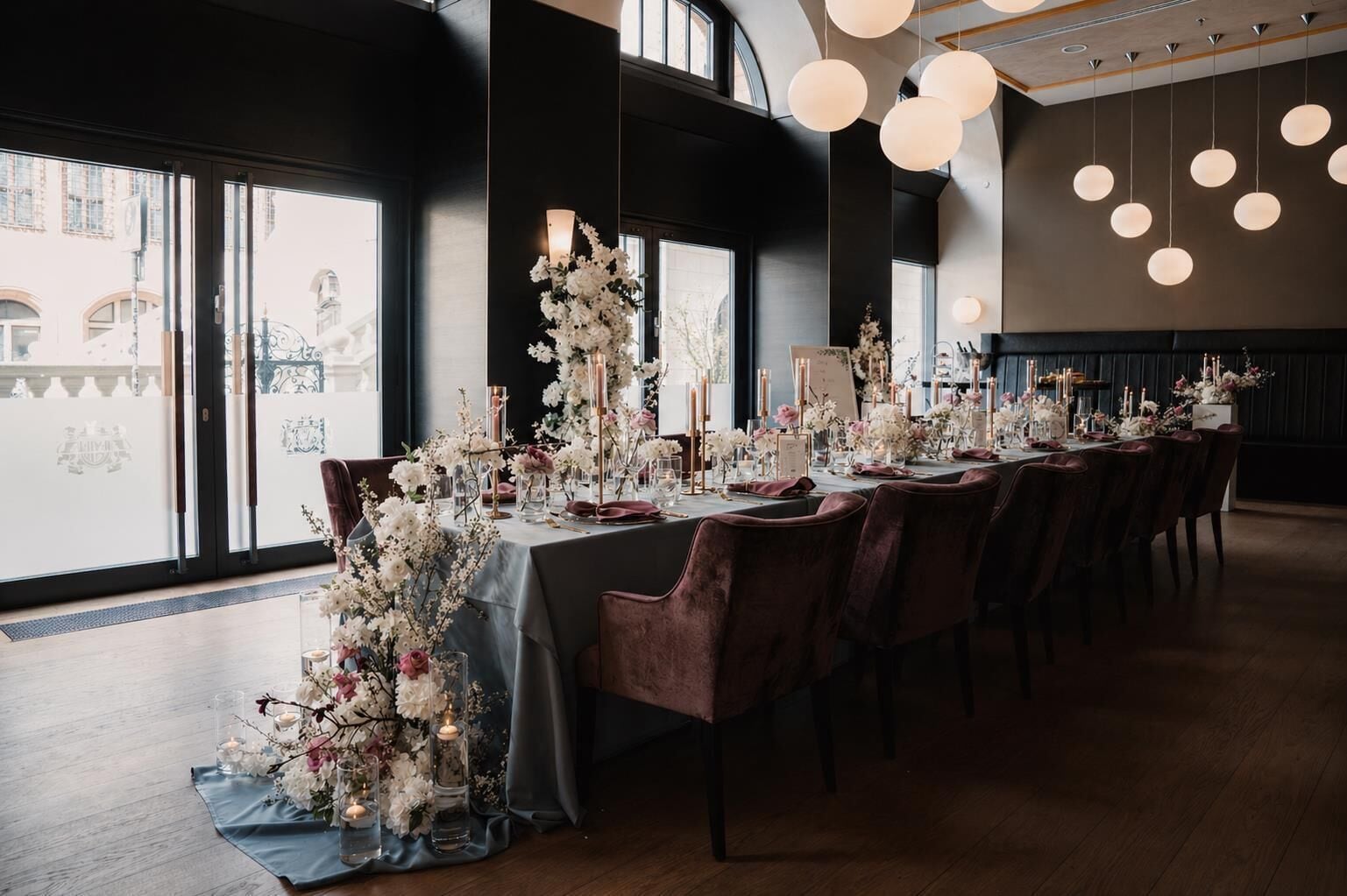 A long dining table with floral centerpieces, candles, and elegant table settings.