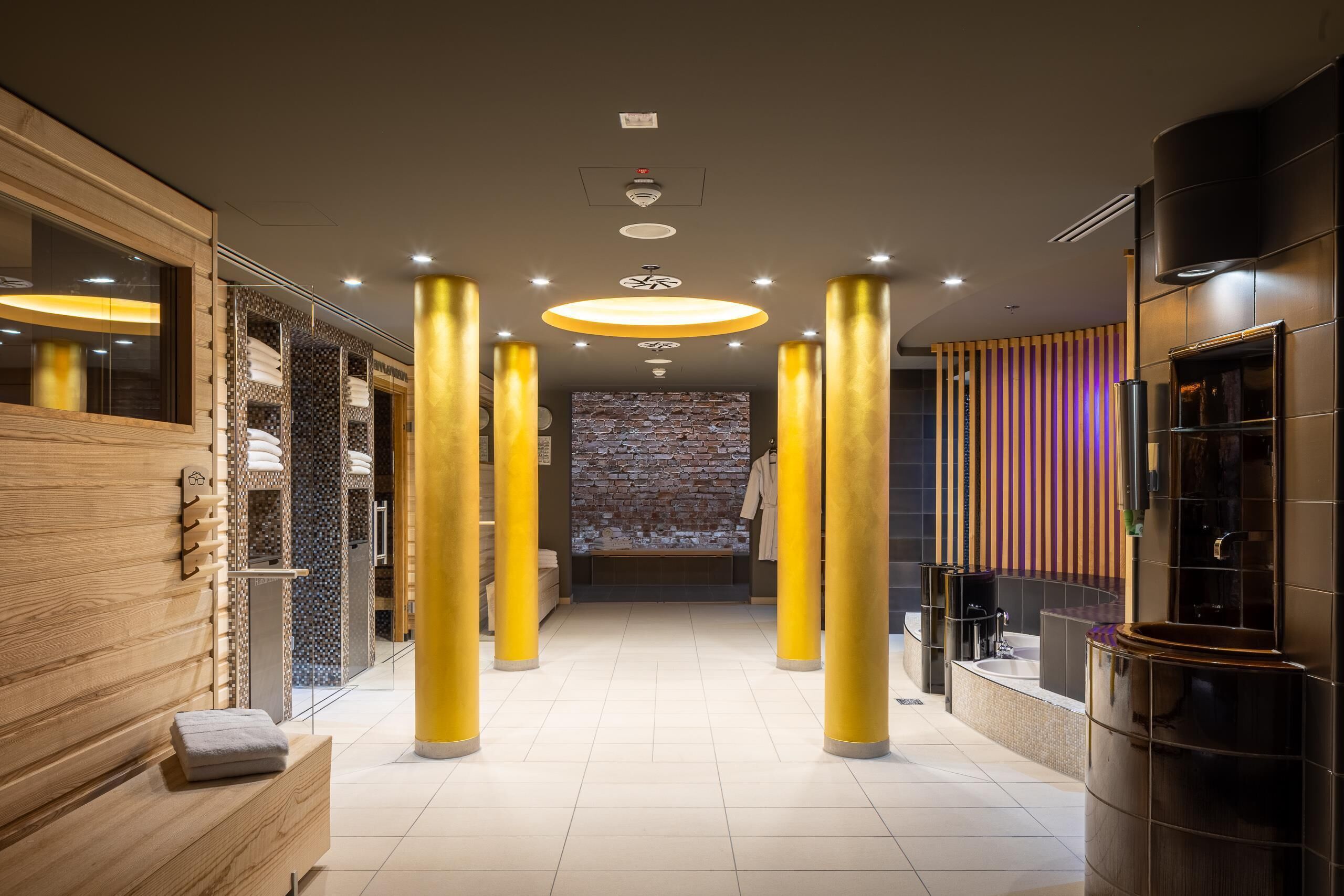 Un lobby moderno de hotel con una zona de estar central, una pared de ladrillo y un mostrador de recepción.