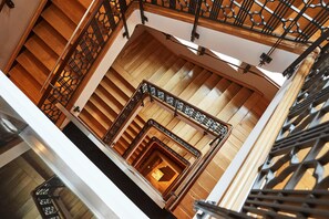 Una escalera de madera con barandilla decorativa y un letrero sobre la puerta.