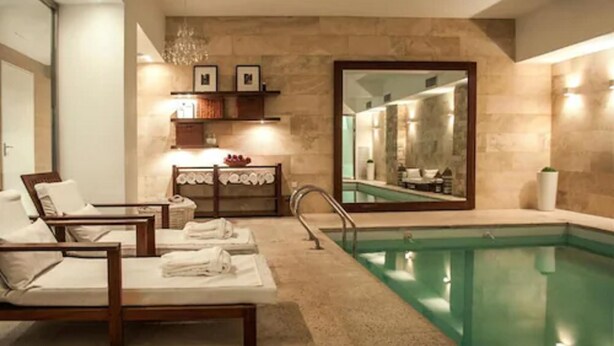 A spa area with a pool, lounge chairs, a vanity with a mirror, and a chandelier. - Awwa Suites and Spa (Buenos Aires)
