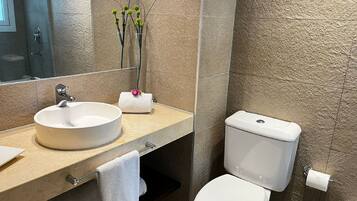 Un baño moderno con un lavabo redondo, un inodoro y un perchero para toallas.