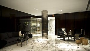A modern living room with a marble floor, dark furniture, and a large pillar. - Awwa Suites and Spa (Buenos Aires)