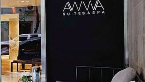 A modern hotel lobby with a glass entrance, a seating area with a sofa and a table, and a sign for 'AMWA SUITES & SPA'. - Awwa Suites and Spa (Buenos Aires)