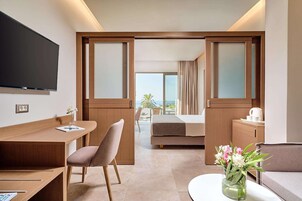 Habitación de hotel con cama, escritorio, silla, televisión y vistas al exterior.