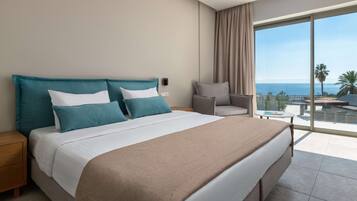 Habitación de hotel con una cama grande, una silla, una mesita y vista al océano.