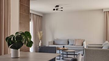 A modern living room with a dining area, grey sofas, a coffee table, and a potted plant.