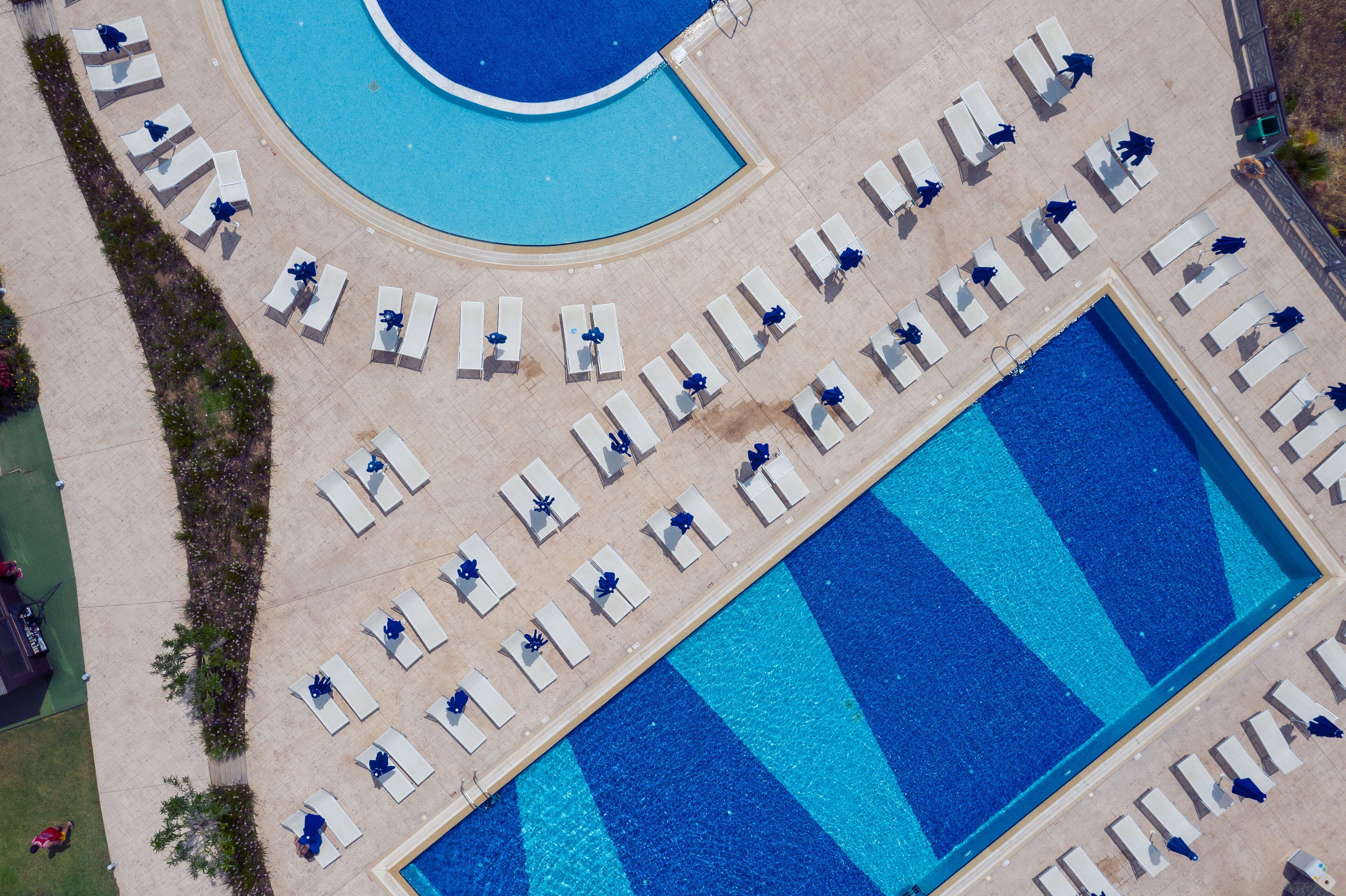 Vue aérienne d’un espace piscine doté de plusieurs chaises longues et d’une grande piscine rectangulaire.