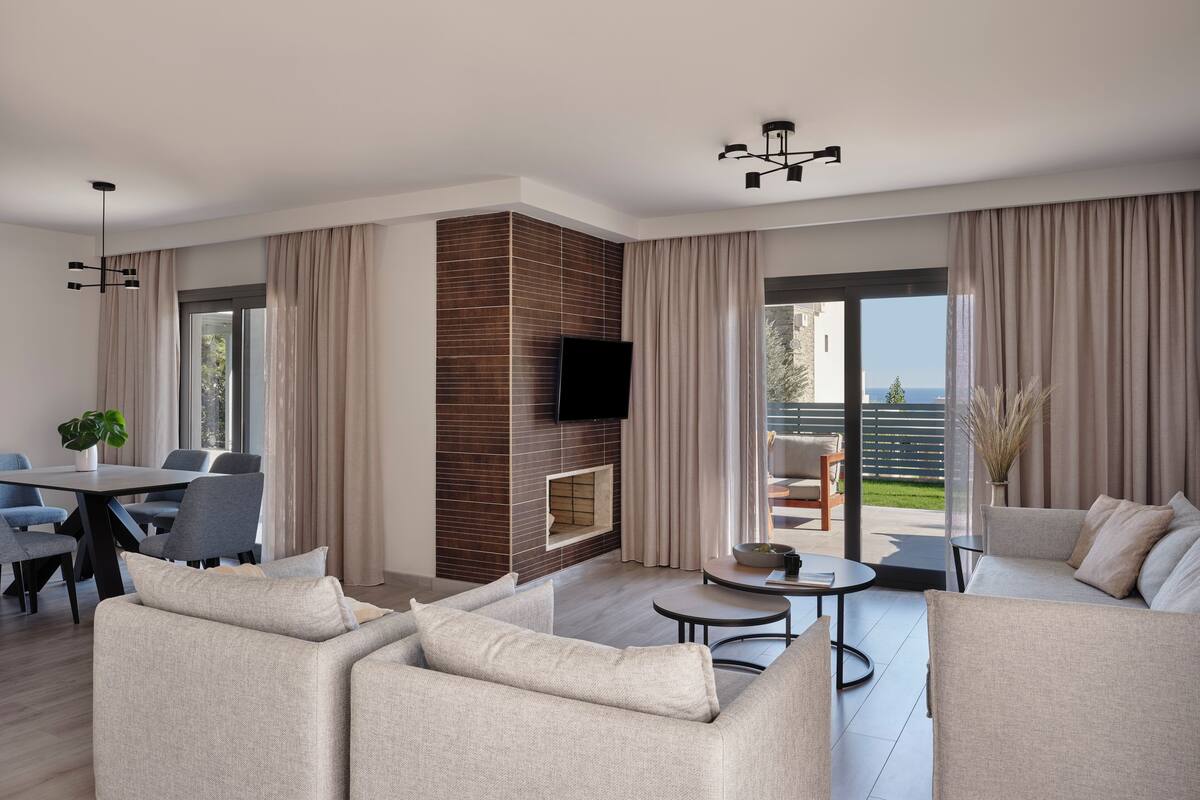 A modern living room with a fireplace, a dining area, and a balcony with a view.