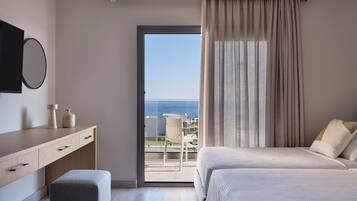 Un dormitorio moderno con una cama grande, un escritorio, una silla y vistas al mar.