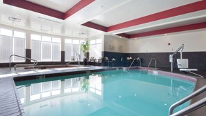 An indoor swimming pool with clear water, safety signs, and a modern design.