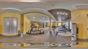 A gym with exercise equipment, a trash can, and a water dispenser.