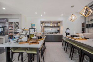 Une cuisine moderne dotée d’un îlot central, de tabourets de bar et d’un espace dédié au café.