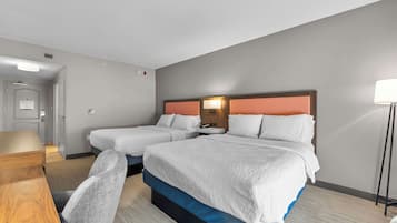 A hotel room with two beds, a desk, and a chair.