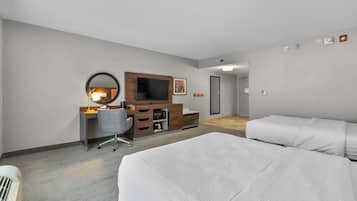 Ein Hotelzimmer mit zwei Betten, einem Schreibtisch mit Stuhl, einem Fernseher und einem Spiegel.
