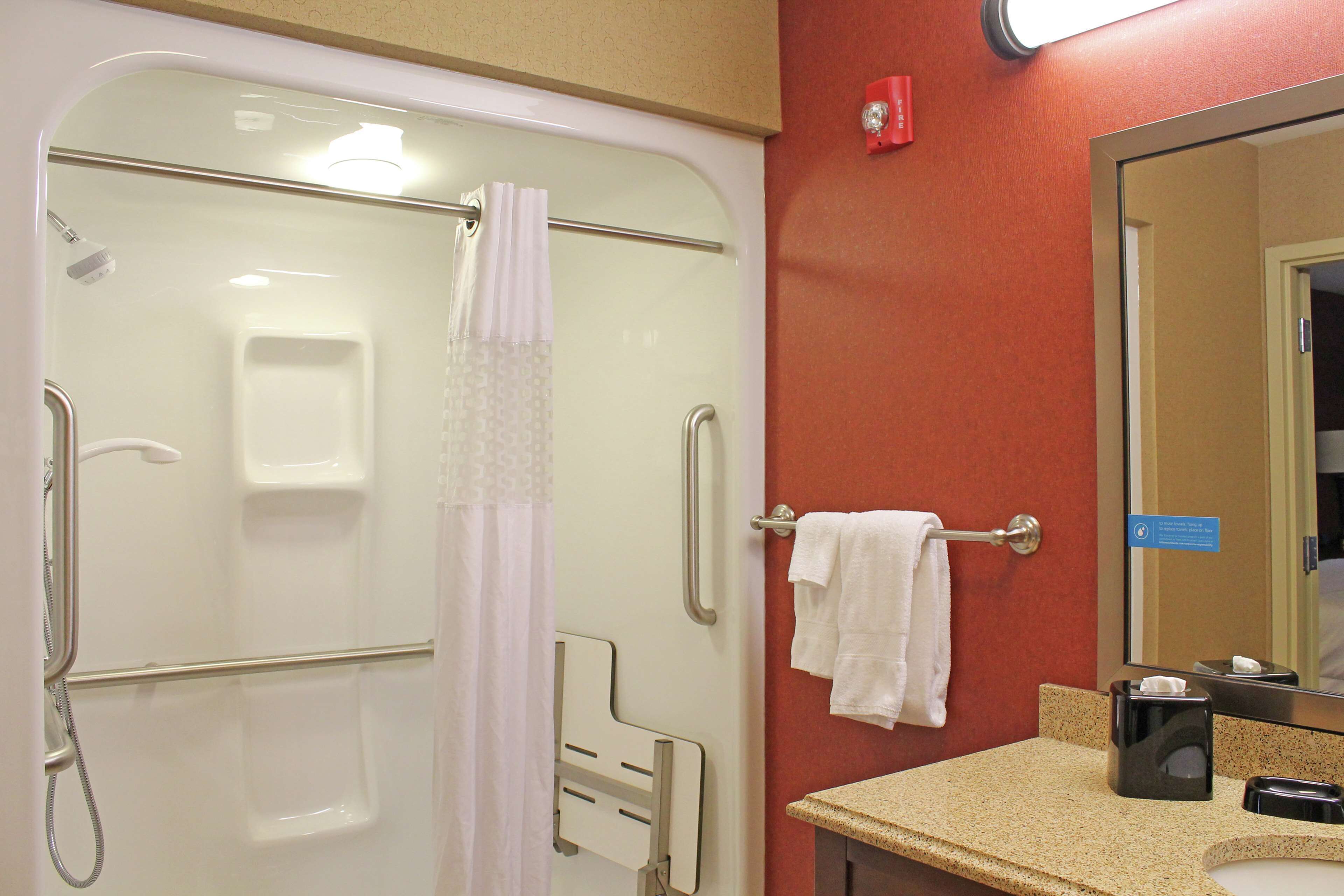 A bathroom with a shower, a sink, and a mirror.