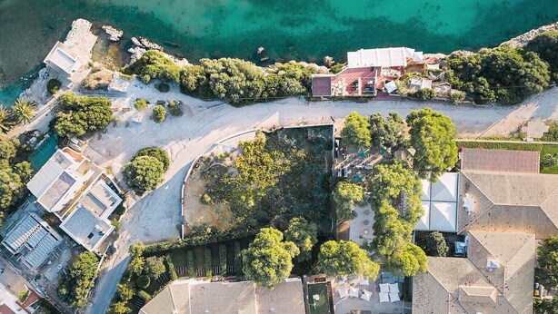 Vue aérienne d’une station balnéaire avec une piscine, des propriétés situées en bord de mer et des bateaux sur l’eau.