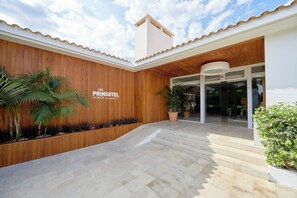 A hotel entrance with a wooden facade, a signboard, and a staircase leading to the entrance. - Prinsotel La Caleta Hotel (Ciutadella de Menorca)
