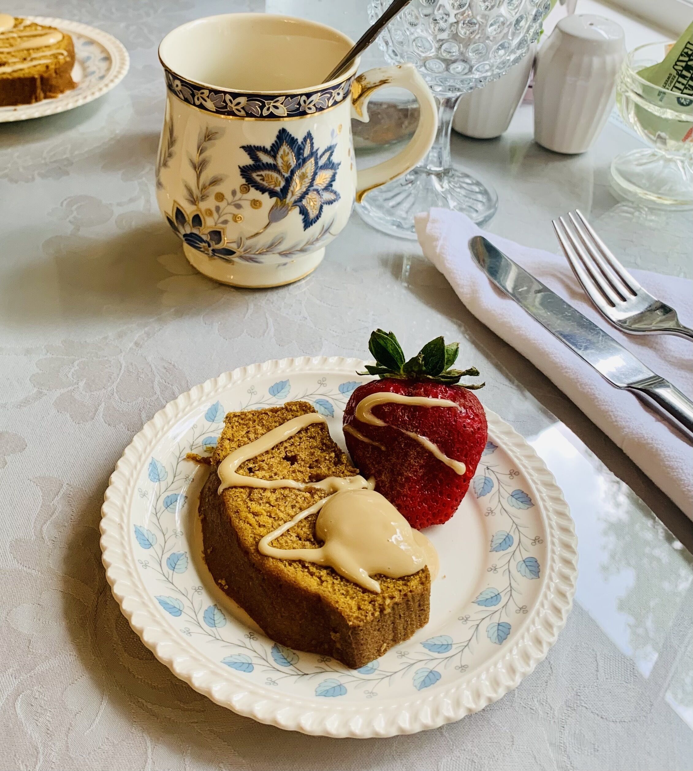A plate with a slice of cake and a strawberry on a floral-patterned plate.