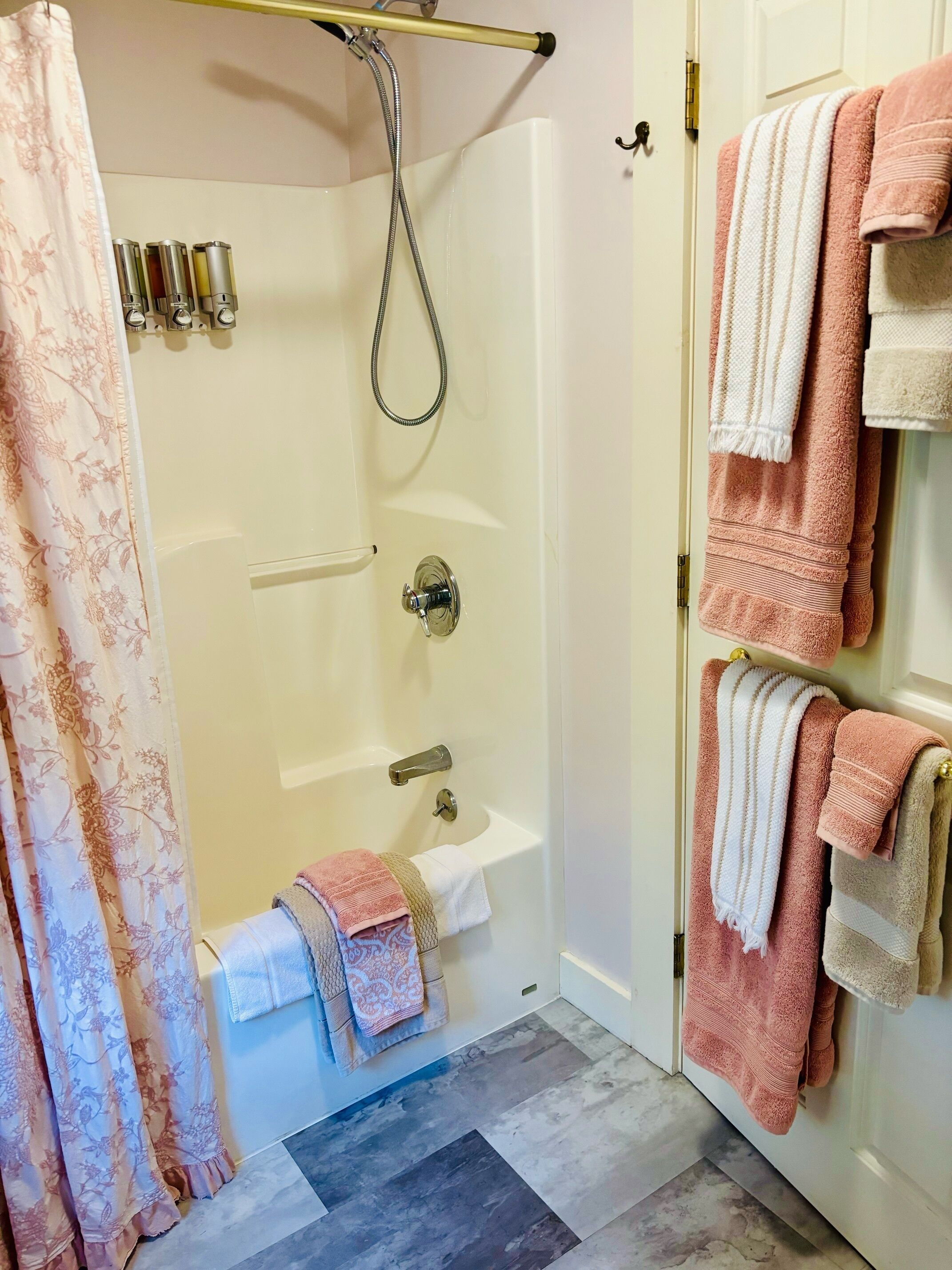 Une salle de bain avec une douche, des toilettes et un lavabo. Des serviettes sont accrochées au mur.