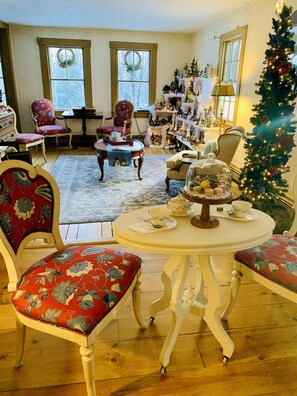 A cozy living room with a Christmas tree, a dining table with a teapot and cups, and a fireplace. - The Buttonwood Inn on Mt. Surprise (Intervale)
