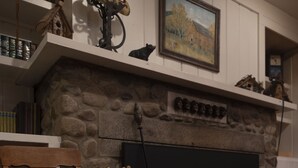 Ein gemütliches Wohnzimmer mit Kamin aus Stein, einem Holzstuhl und einem Fernseher.