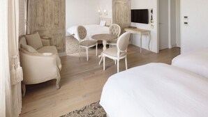 A hotel room with a bed, a sofa, a dining table with chairs, a TV, and a chandelier. - Hotel Plumm (Yokohama)