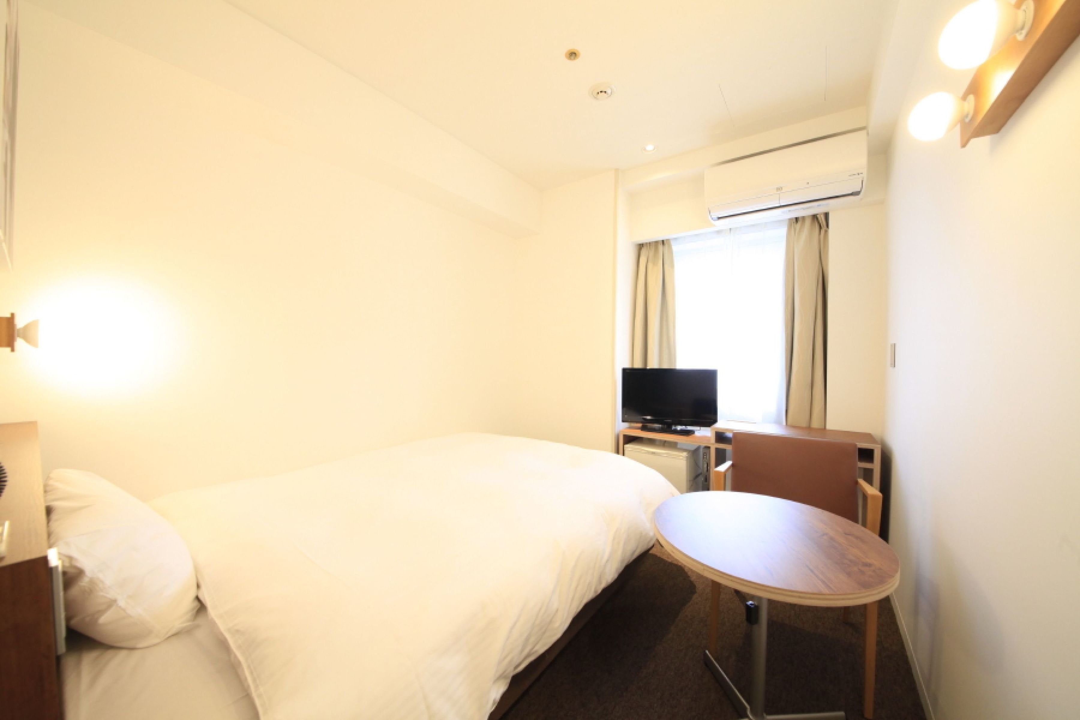 A hotel room with a bed, a TV, a desk, and a chair.