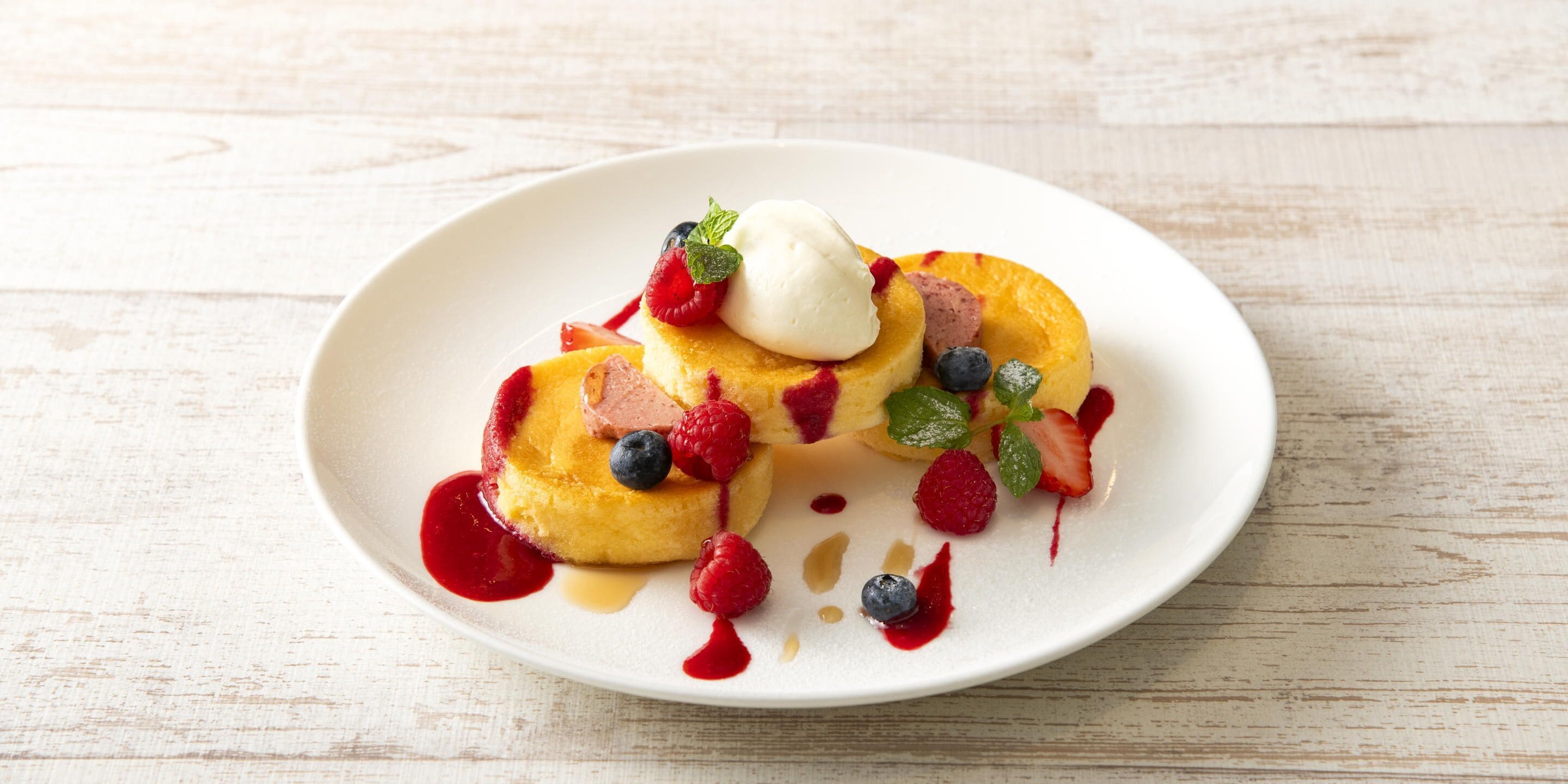 A plate of pancakes with berries and a dollop of cream.