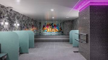 A modern spa area with marble walls, a colorful mural, and teal seating.