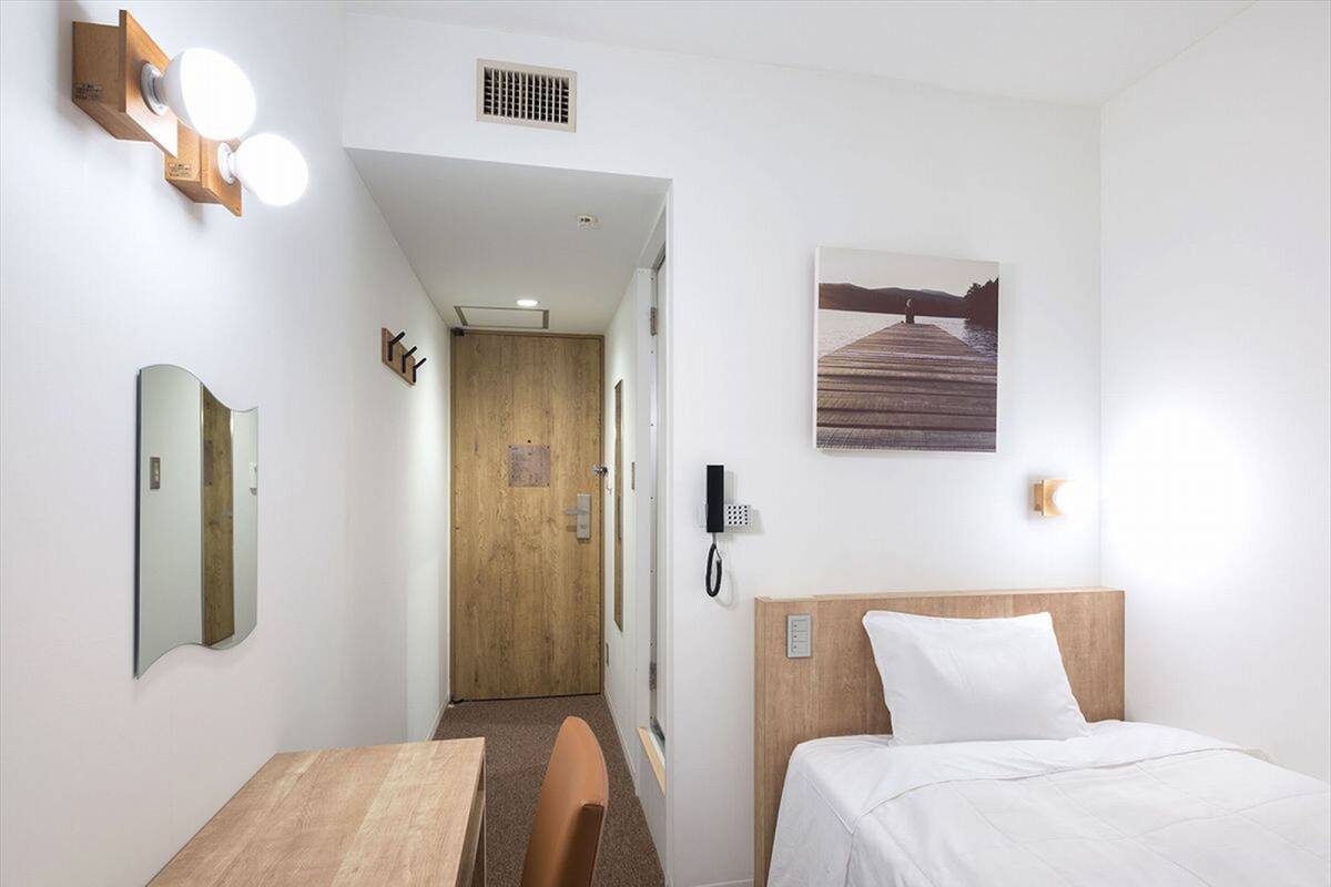 A hotel room with a wooden bed, a desk, a chair, a mirror, a phone, and a picture of a dock on the wall.
