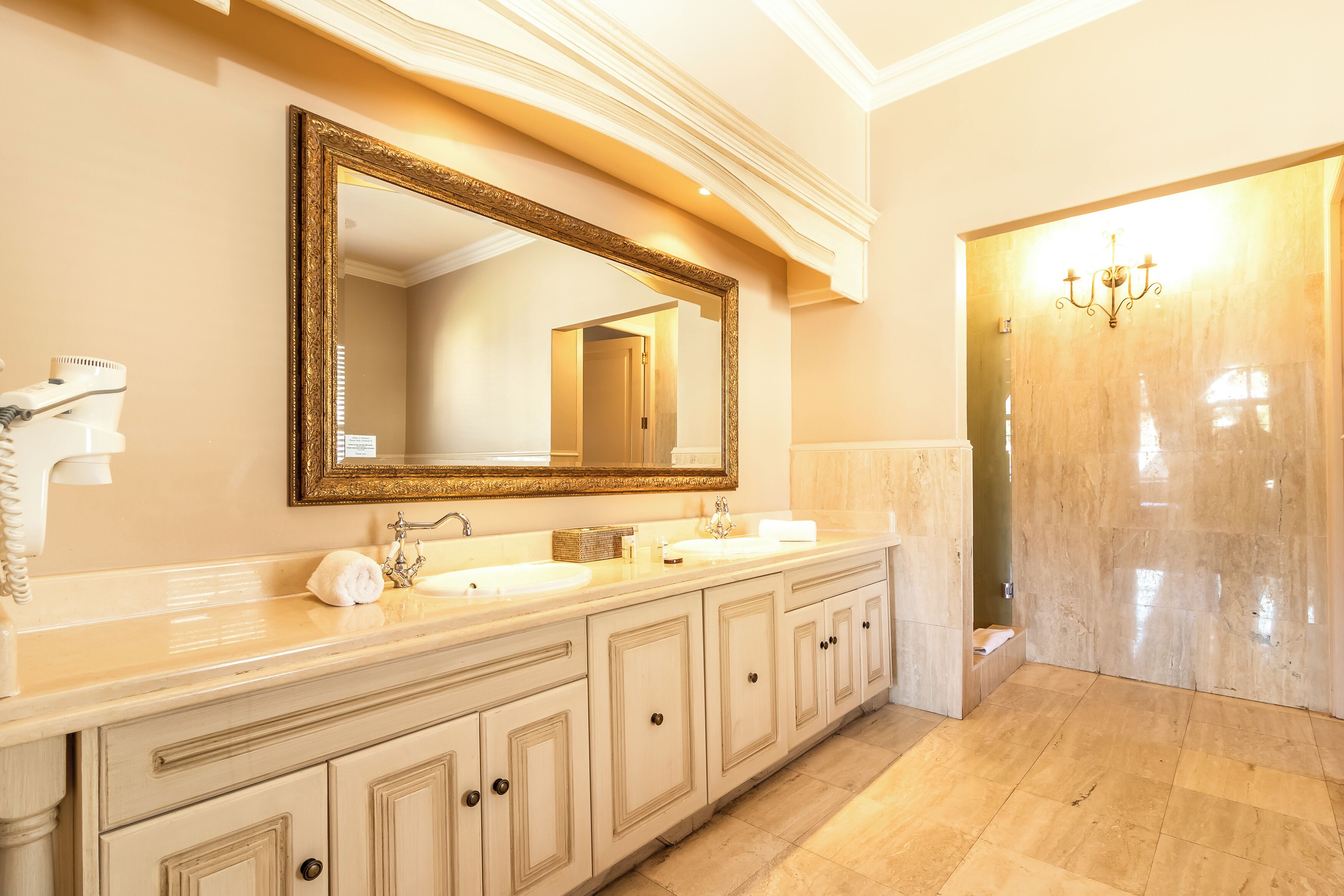 A bathroom with a large mirror, two sinks, and a vanity with drawers.